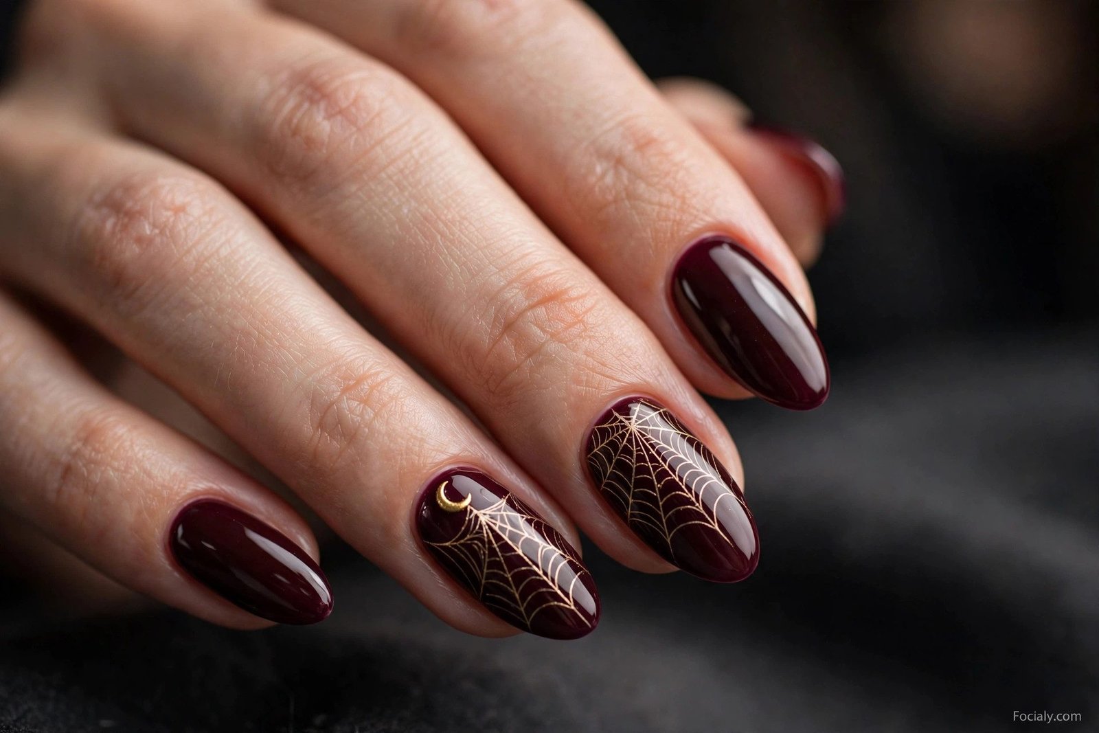 Deep burgundy Halloween nails with gold spiderweb line art