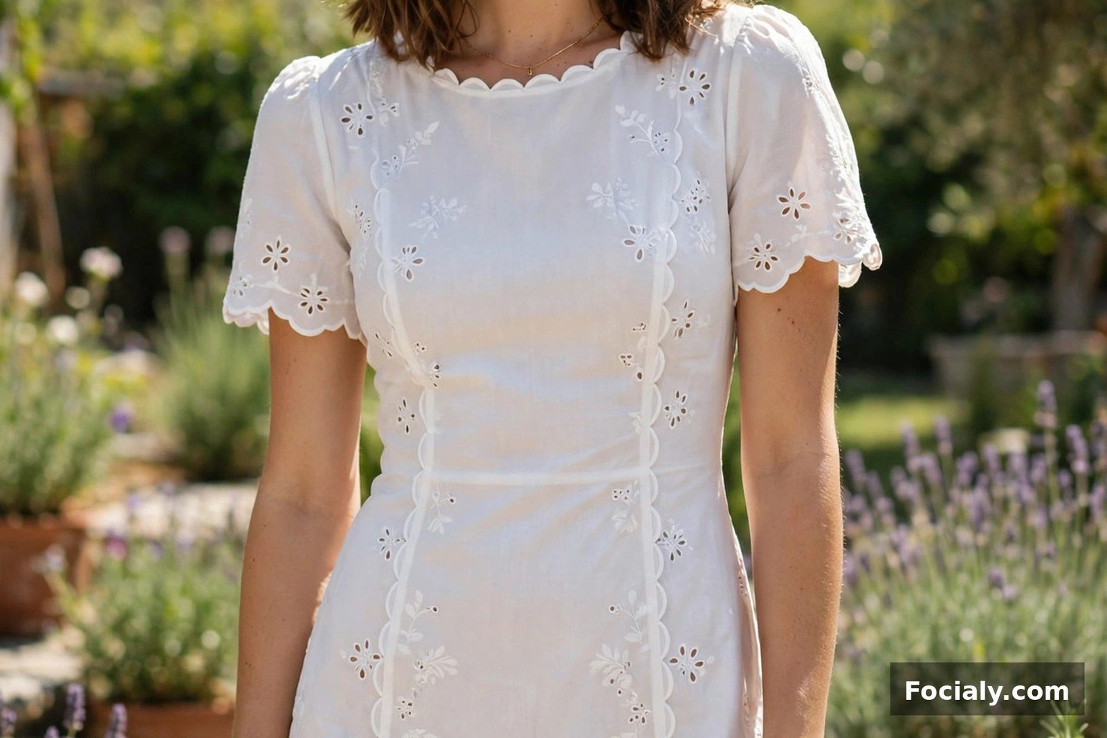 Woman in a white broderie anglaise mini dress with scalloped edges