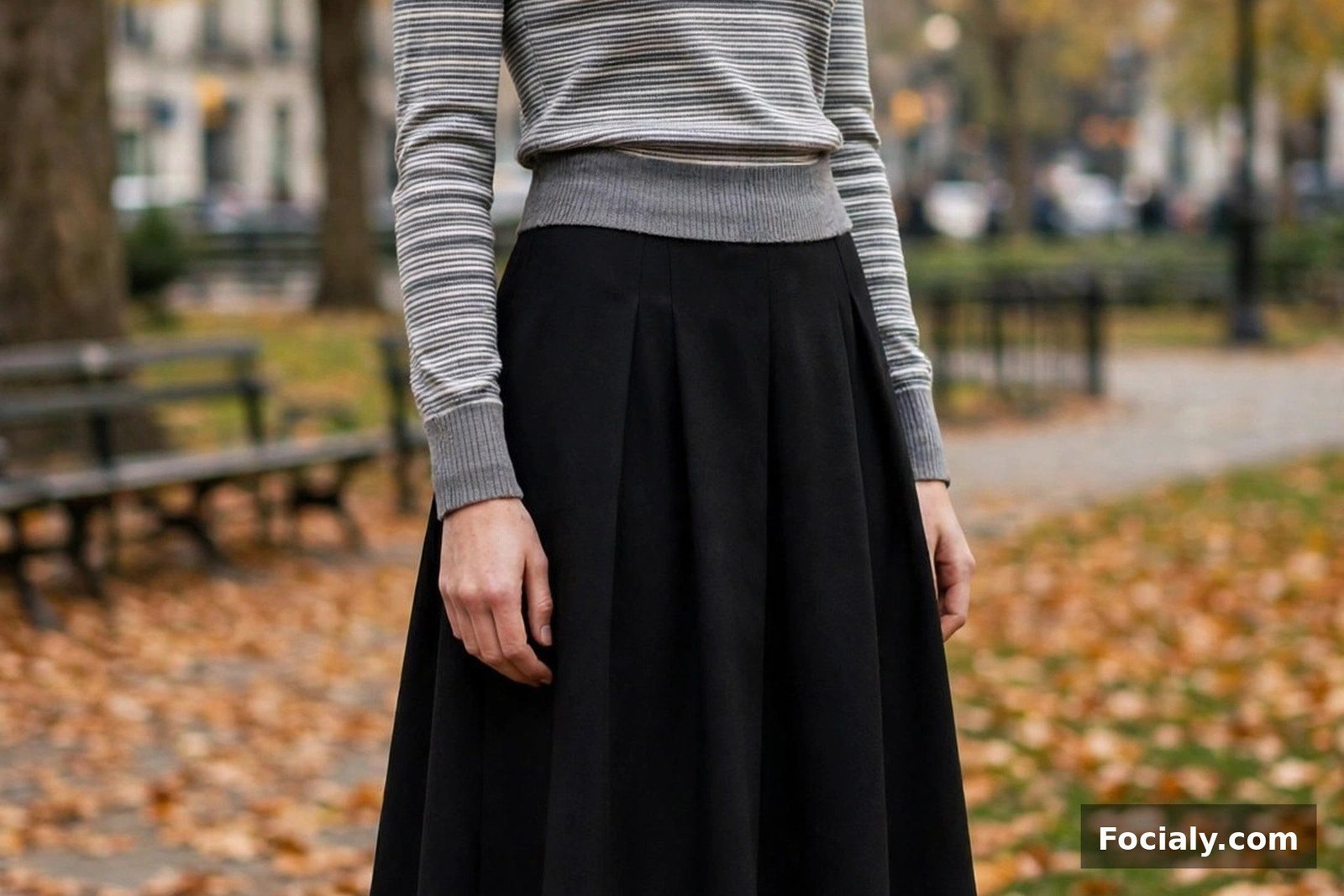 Woman wearing a black A-line midi skirt with a fitted striped sweater and Mary Janes